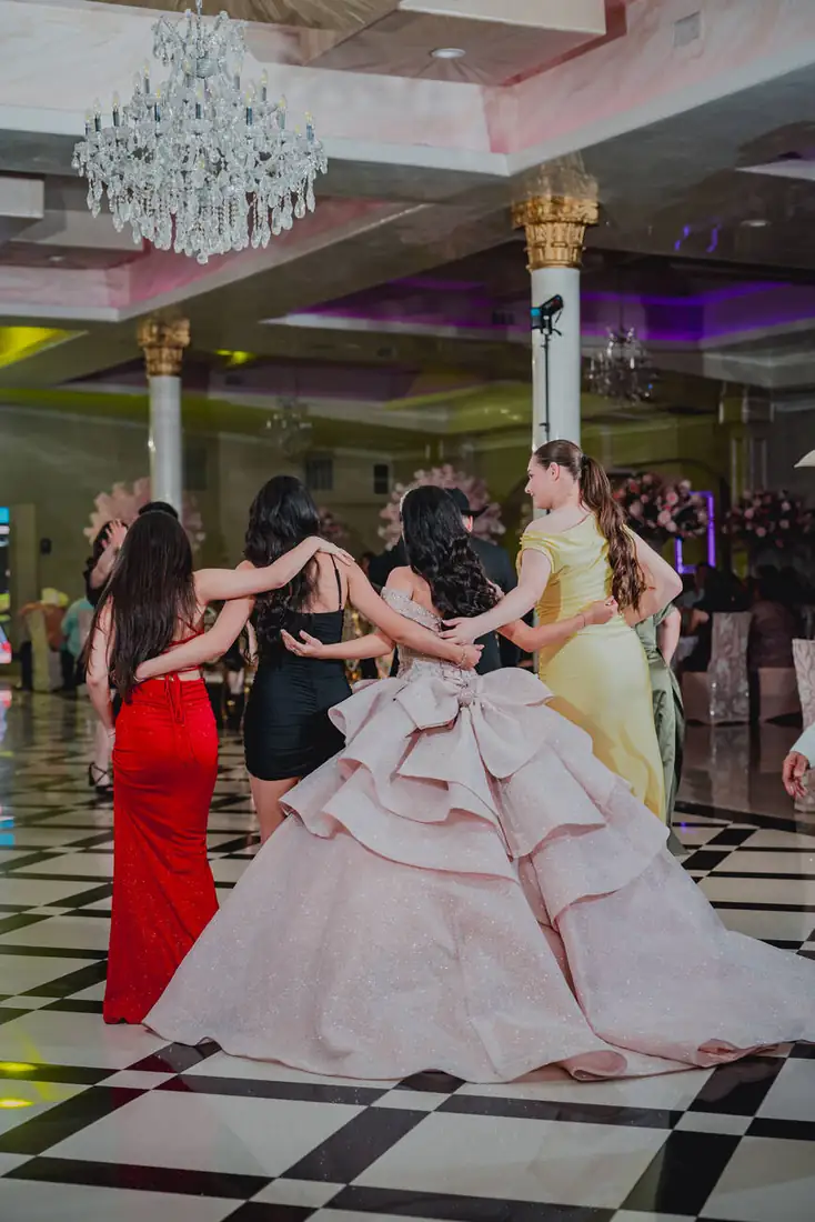 Quinceañera dancing with family under chandeliers at The Grand Villa